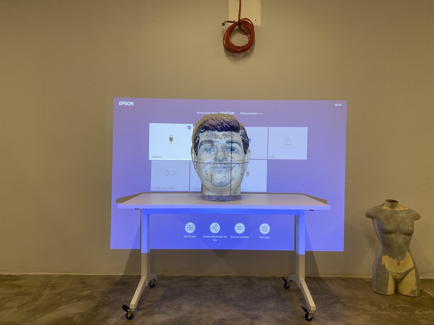Projetor Epson configurado na sala, com o rosto físico posicionado na frente da tela