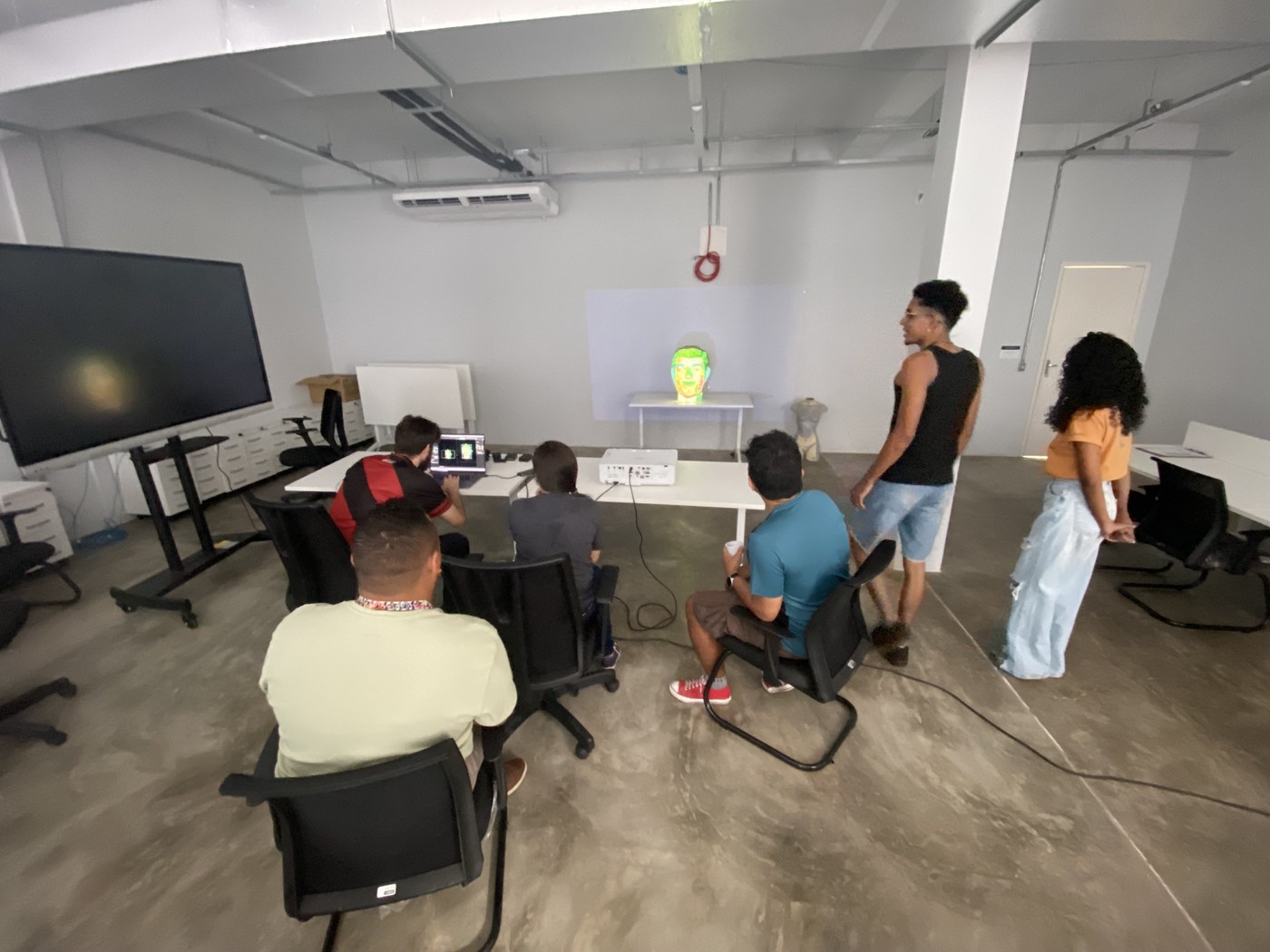Turma acompanhando a projeção ao vivo no rosto físico durante a aula
