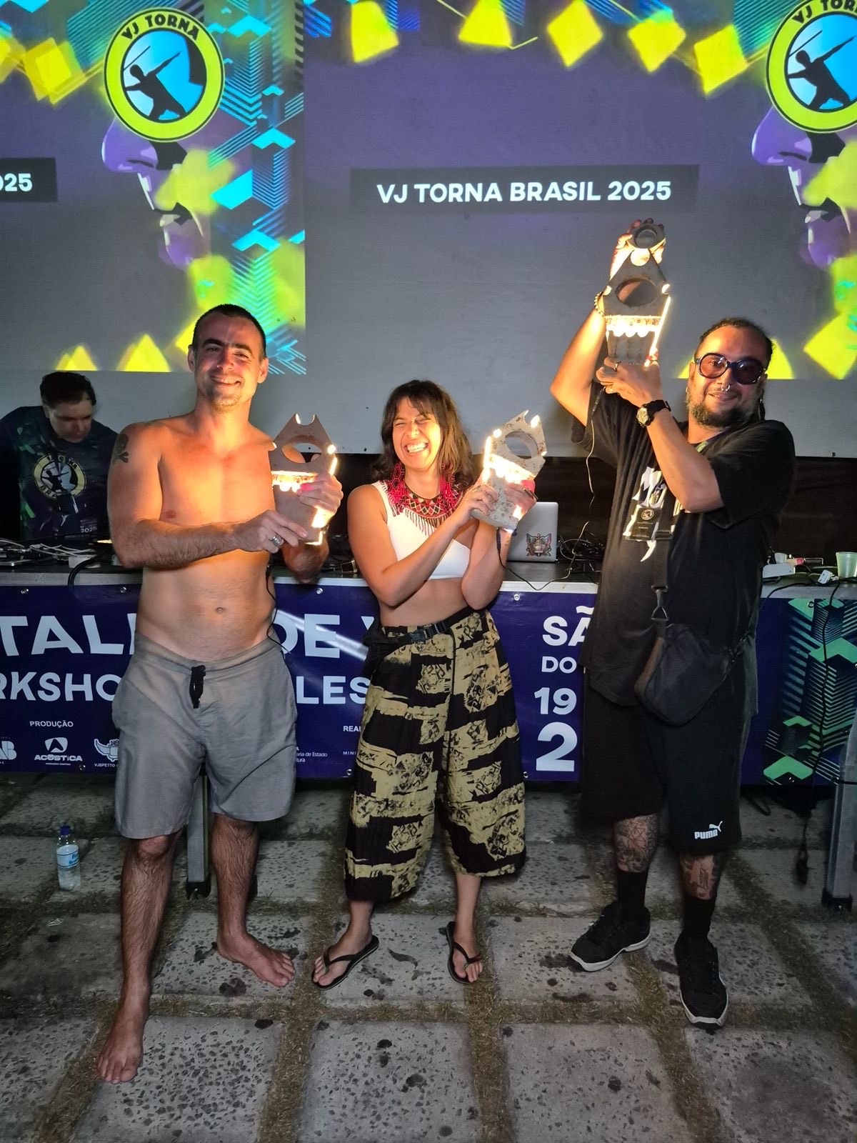 Pódio do VJ Torna Brasil 2025: Valentino (1º lugar), Carol Santana (2º lugar) e VJ Guabiru (3º lugar) erguendo os troféus iluminados