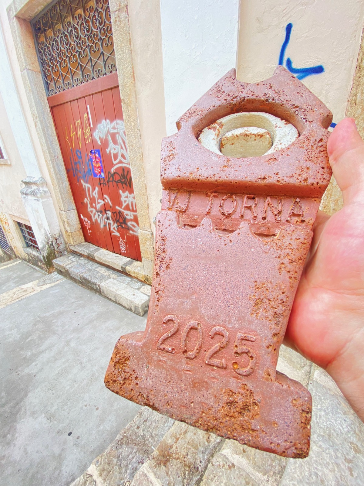 Detalhe do troféu enferrujado, gravado 'VJ TORNA' e '2025'