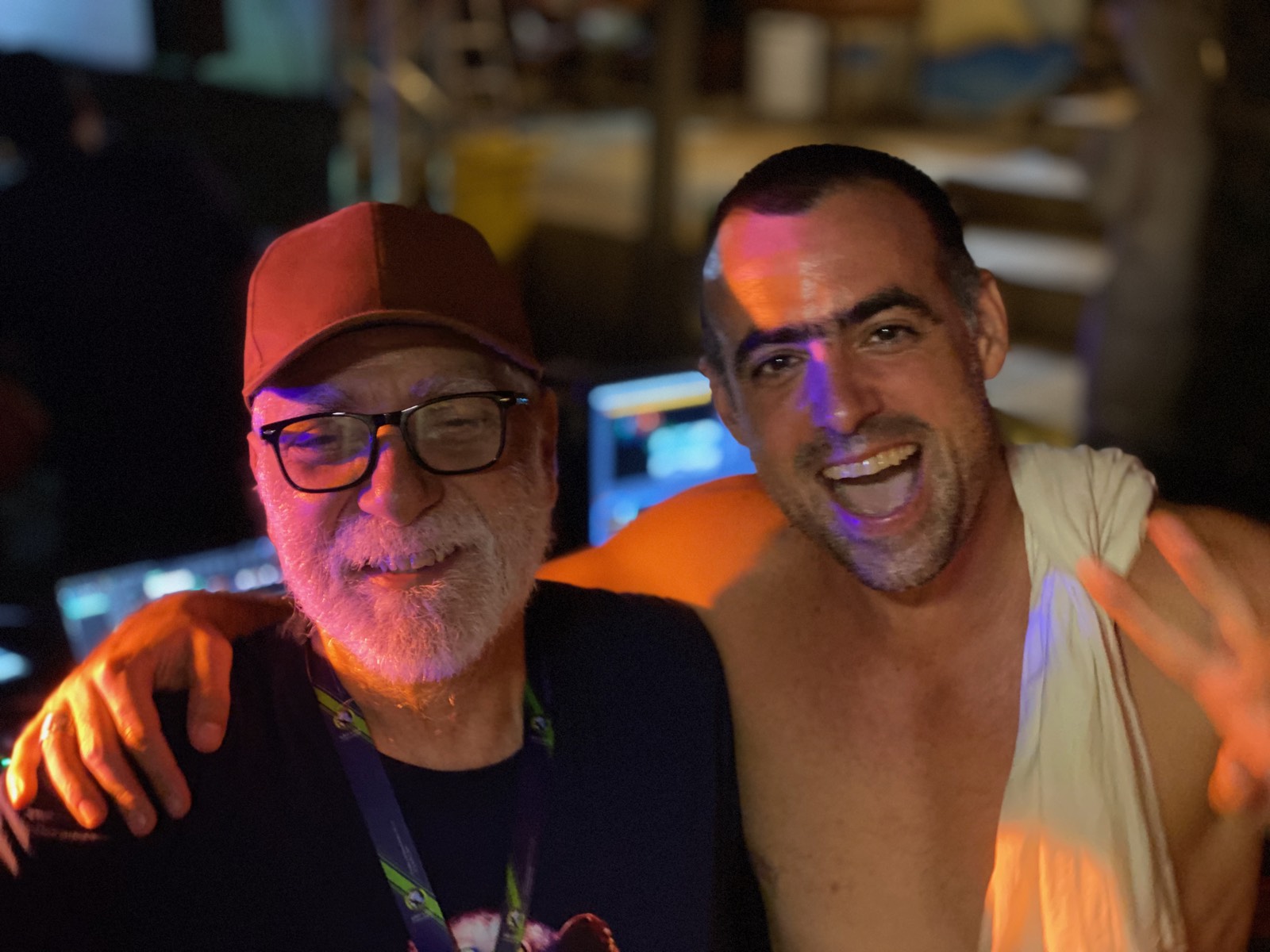 Selfie de noite com amigo de boné e óculos, luz vermelha ao fundo