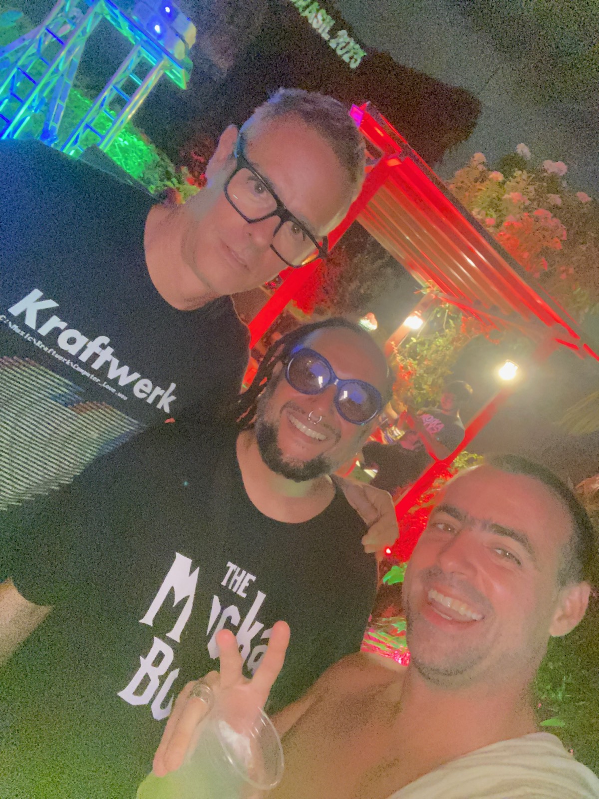 Selfie em trio de noite, um deles com camiseta do Kraftwerk