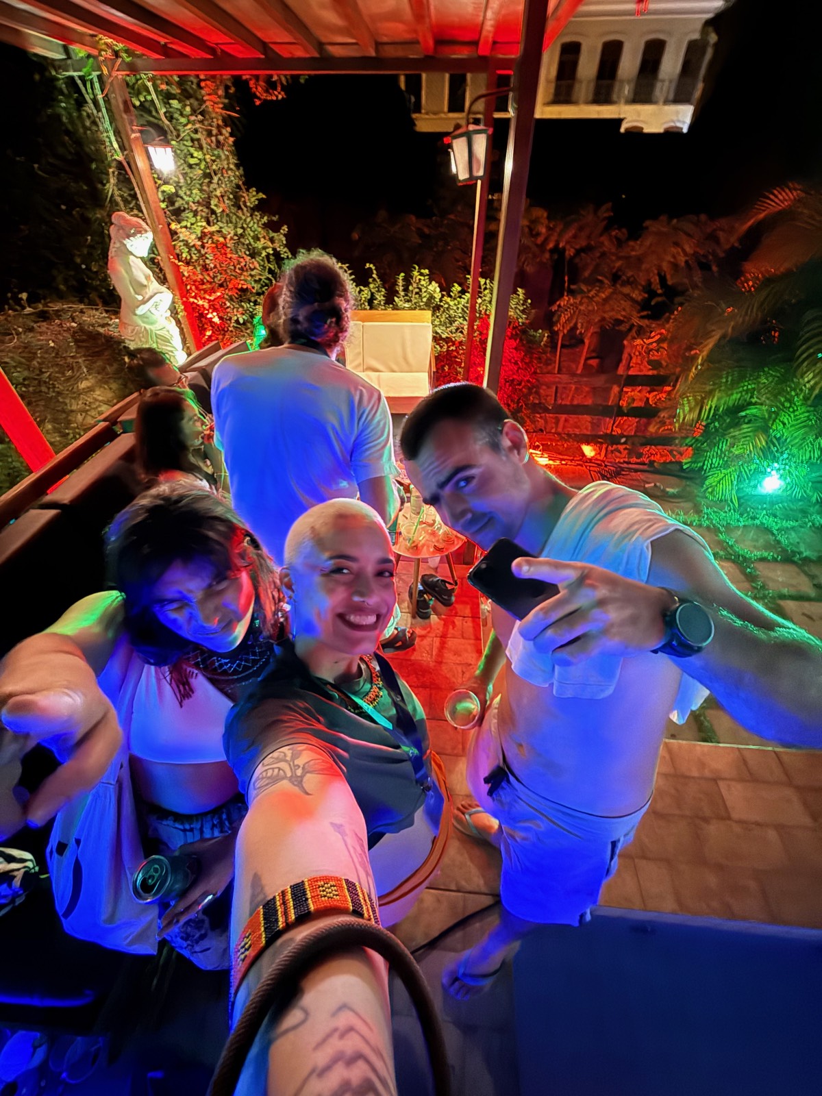 Outro ângulo do grupo de amigos reunido de noite, pátio da pousada ao fundo